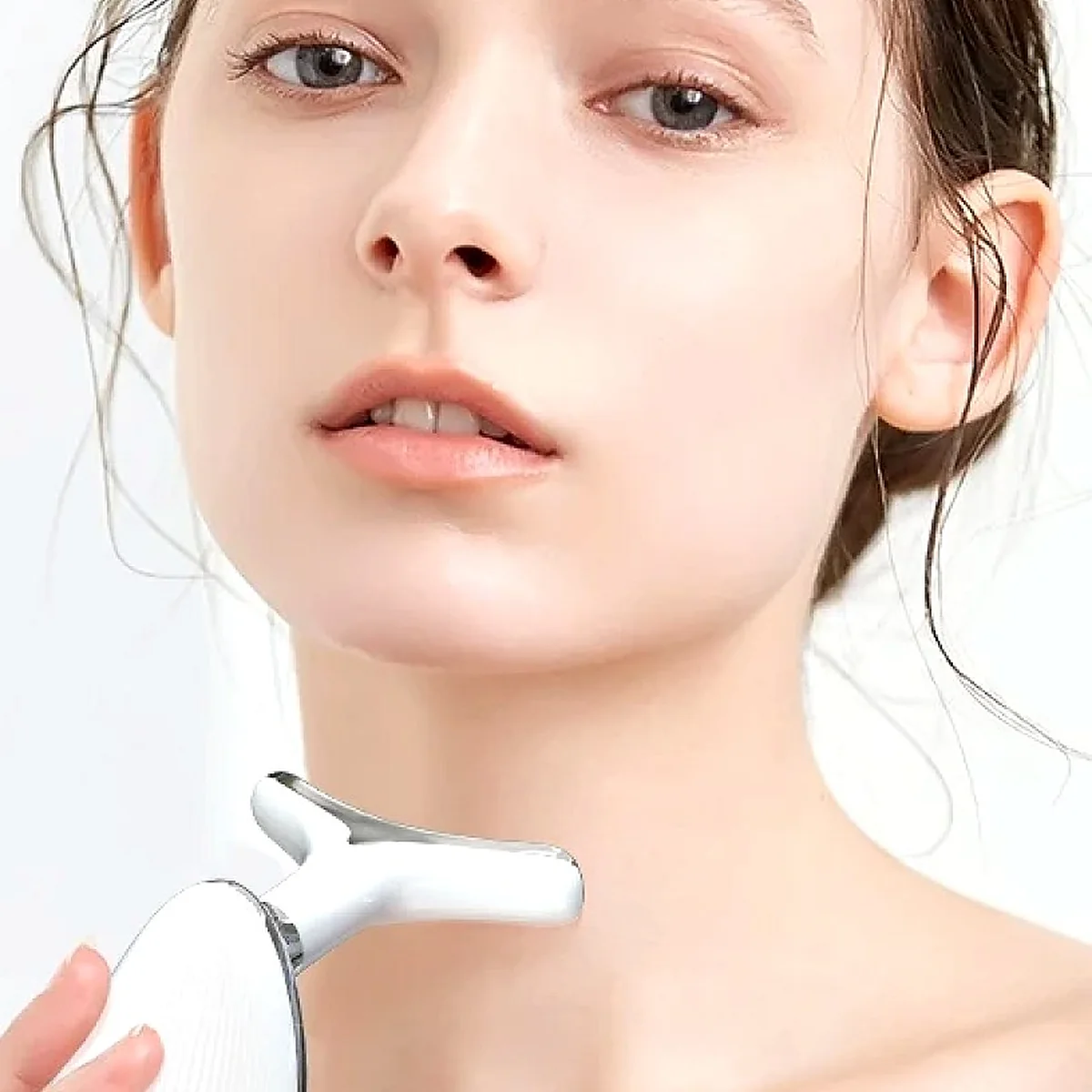 Woman gliding the ANLAN EMS device along her jawline and neck