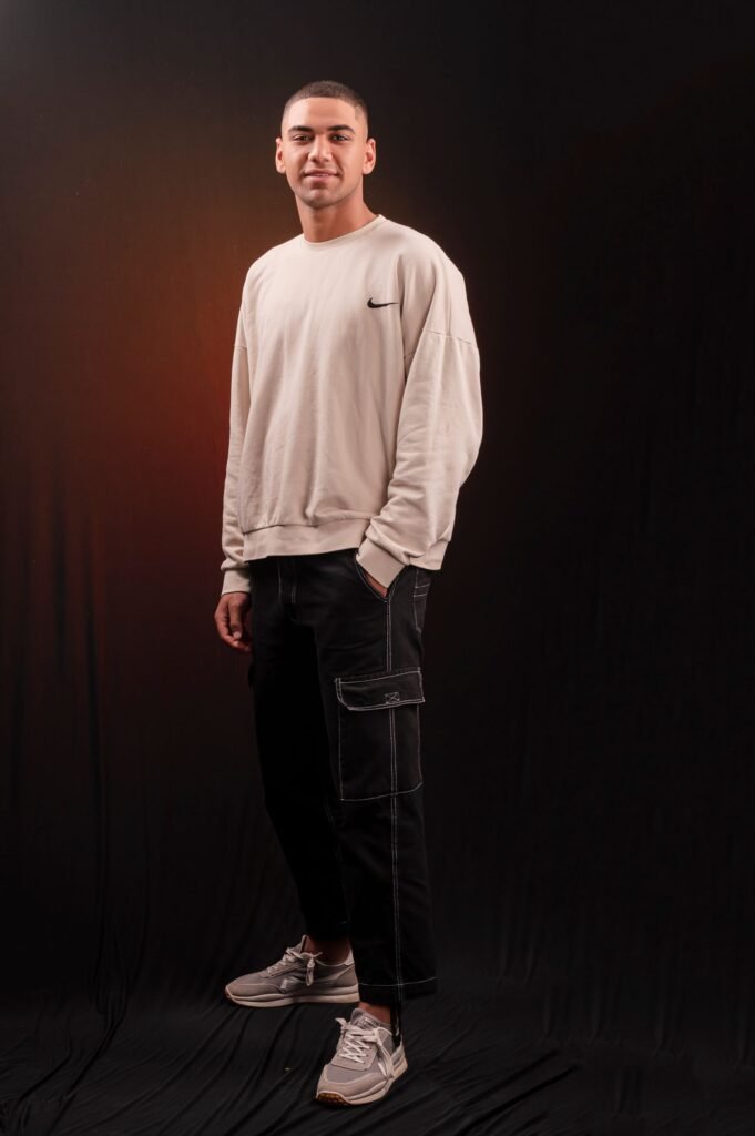 Man wearing a light crewneck sweatshirt with black cargo pants