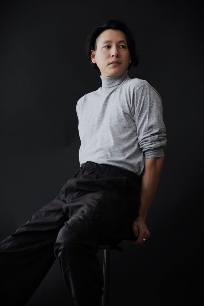 Man wearing a light gray high-neck sweatshirt and dark pants
