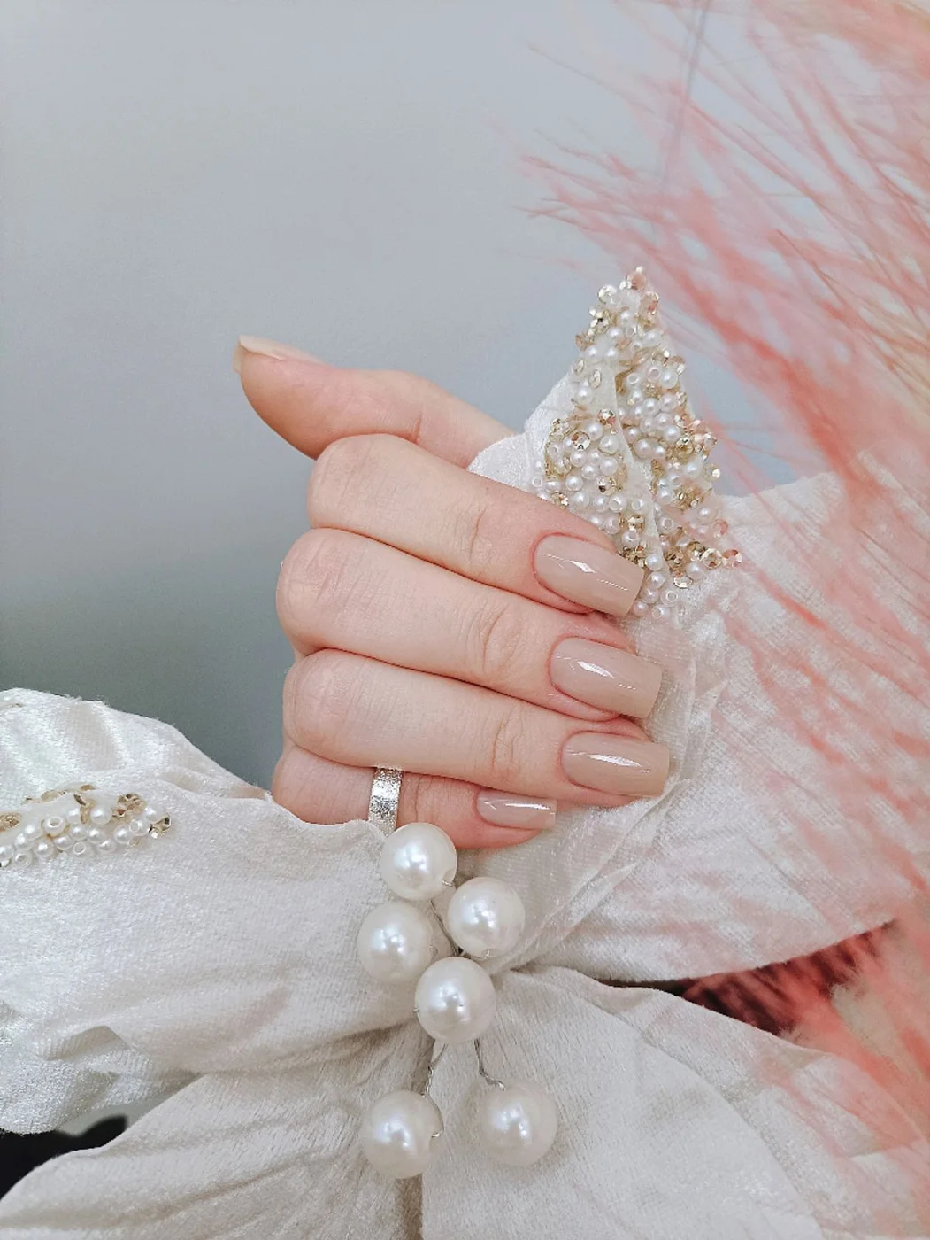 Beige manicure with decorative pearls and soft fabric