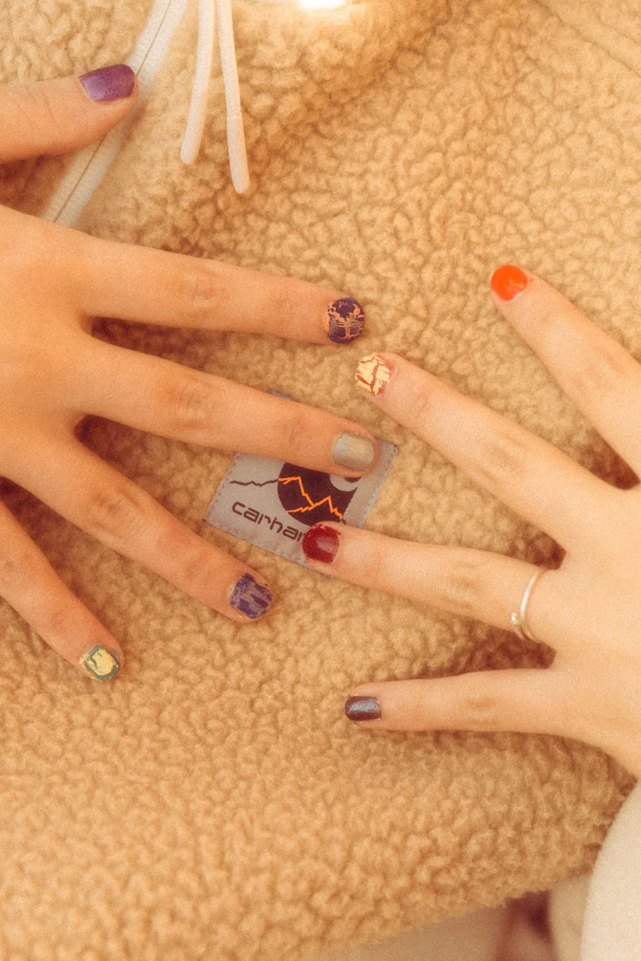 Mixed colourful patterned nails above a textured cream background