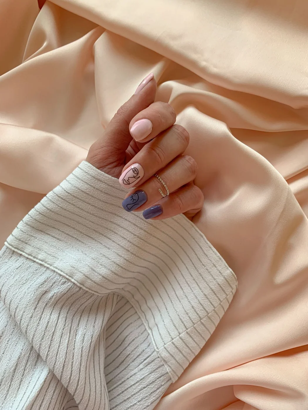 Lilac patterned accent nails with soft neutral nails on satin fabric