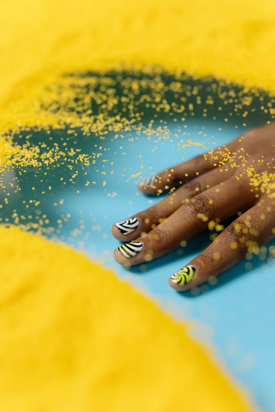 Black and white graphic nail art with bright yellow accents