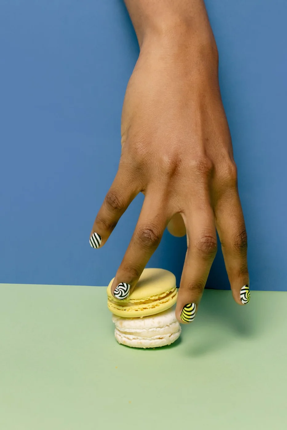 Graphic striped nails holding colourful macarons